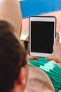 A young man in sunglasses holds a tablet in his hands. Freelancer job concept on the beach and vacation Royalty Free Stock Photo