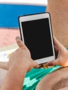 A young man in sunglasses holds a tablet in his hands. Freelancer job concept on the beach and vacation Royalty Free Stock Photo