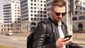 A young man in sunglasses looks at the phone in the city. City navigation Royalty Free Stock Photo