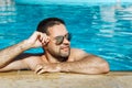 Young man in sunglasses resting relaxed on edge of swimming pool Royalty Free Stock Photo