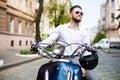 Young man in sunglasses riding scooter along the street city