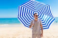 Young man in sunglasses walking on the beach with sun solar umbrella on sea resort. Summer vocation Royalty Free Stock Photo