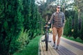 Young Man In Sunglasses Walking With Bicycle On Summer Park