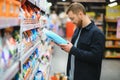 Young man in the supermarket in the household chemicals department. Large selection of products. A brunette in a glasses Royalty Free Stock Photo