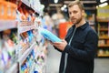 Young man in the supermarket in the household chemicals department. Large selection of products. A brunette in a glasses Royalty Free Stock Photo