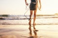 Young man Surfer taking surfboard and comming with long surf board to waves on the evening sunset sky background. Close up legs