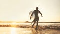 Young man Surfer taking surfboard and running with long surf board to waves on the evening sunset sky background. Active holidays Royalty Free Stock Photo