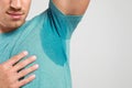 Young man with sweat stain on his clothes against light background. Using deodorant Royalty Free Stock Photo