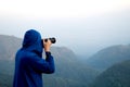 Young man in sweater with hood taking a photo on top of mountain at Doi Ang Khang Chiang Mai Thailand