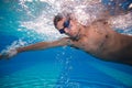 Young man swimming the front crawl in a pool