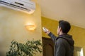 Young man switching on the air conditioner