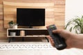 Young man switching channels on TV set with remote control at home, closeup Royalty Free Stock Photo