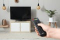 Young man switching channels on TV set with remote control at home, closeup Royalty Free Stock Photo