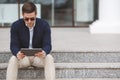 Young man with tablet computer sitting on stairs Royalty Free Stock Photo