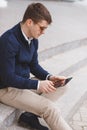 Young man with tablet computer sitting on stairs Royalty Free Stock Photo