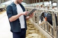 Young man with tablet pc and cows on dairy farm Royalty Free Stock Photo