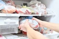 A young man takes out convenience foods from the freezer to prepare dinner in the microwave