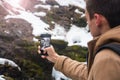 A young man takes a picture of a waterfall on a mobile phone in Royalty Free Stock Photo