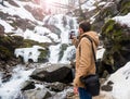 A young man takes a picture of a waterfall on a mobile phone in Royalty Free Stock Photo