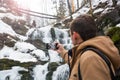 A young man takes a picture of a waterfall on a mobile phone in Royalty Free Stock Photo