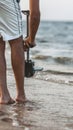 Young man takes steps on wet sand with a camera attached to a steadicam, a videographer shoots video walking barefoot along the