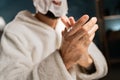 A young man taking care of the skin of his hands in the evening in the bedroom applies moisturizing cream to his hands Royalty Free Stock Photo