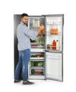 Young man taking juice out of refrigerator on white Royalty Free Stock Photo