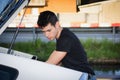 Young man taking luggage and bag out of car trunk Royalty Free Stock Photo