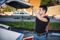 Young man taking luggage and bag out of car trunk Royalty Free Stock Photo