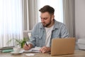 Young man taking notes during online webinar at table indoors Royalty Free Stock Photo
