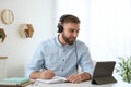 Young man taking notes during online webinar at table indoors Royalty Free Stock Photo