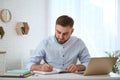 Young man taking notes during online webinar at table Royalty Free Stock Photo