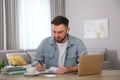 Young man taking notes during online webinar at table Royalty Free Stock Photo