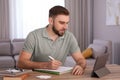 Young man taking notes during online webinar at table Royalty Free Stock Photo