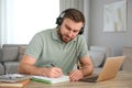 Young man taking notes during online webinar at table Royalty Free Stock Photo
