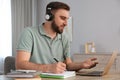 Young man taking notes during online webinar at table Royalty Free Stock Photo