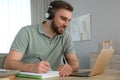 Young man taking notes during online webinar at table indoors Royalty Free Stock Photo