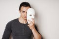 Young man taking off white mask revealing face and identity Royalty Free Stock Photo