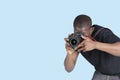 Young man taking photo through digital camera over blue background Royalty Free Stock Photo