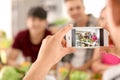 Young man taking photo of his friends in kitchen Royalty Free Stock Photo