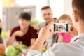 Young man taking photo of his friends in kitchen Royalty Free Stock Photo