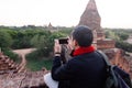 Young man taking a photo with mobile phone in temple stupa scene behind in Bagan, Myanmar. Royalty Free Stock Photo