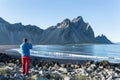 Young man taking a photo to Vestrahorn mountain in Stokksnes Peninsula, Iceland.