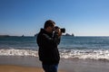 Young man taking a picture with a DSLR camera front shot at the beach Royalty Free Stock Photo