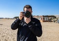 Young man taking a picture with a DSLR camera front shot at the beach Royalty Free Stock Photo