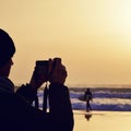Young man taking a picture in front of the sea at dusk Royalty Free Stock Photo