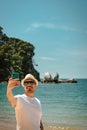 Young man taking picture with mobile at Split Apple Rock. Abel Tasman National Park, New Zealand Royalty Free Stock Photo