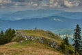 Young man taking pictures of the surrounding view. Scenic summer landscape of the mountains from above.