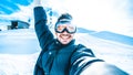 Young man taking selfie picture with smart cell phone hiking mountain on snowy slope - Happy skier having fun Royalty Free Stock Photo