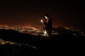 Young man taking selfie on top of the hill observing the night city view. Royalty Free Stock Photo